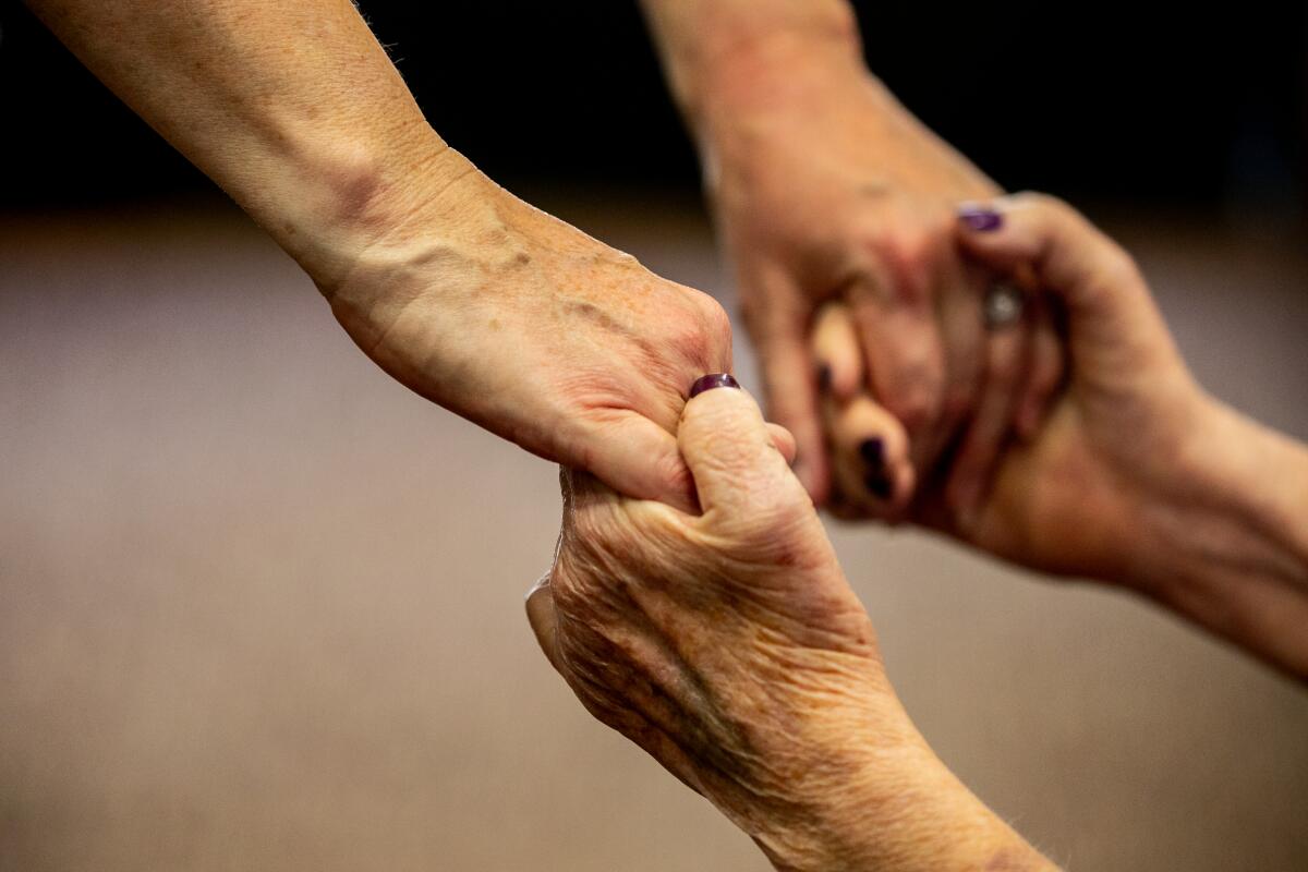 Mother and daughter grasp hands as they meet at St. Paul's Senior Services Nursing and Rehabilitation Center.