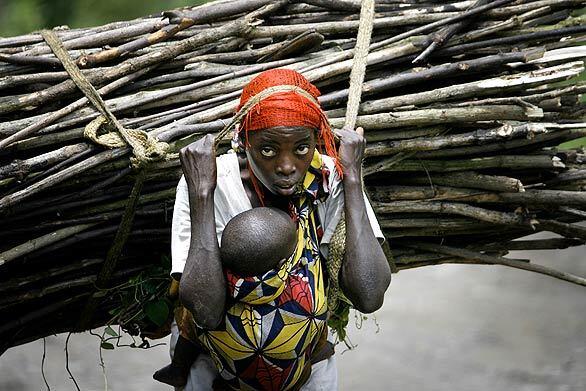 A woman carries wood and her 18-month-old daughter on the road linking Rupango to Sake in eastern Congo. The woman, named Furah, walks nearly 10 miles every day, crossing from a rebel-controlled area to the government-held town of Sake to sell wood.