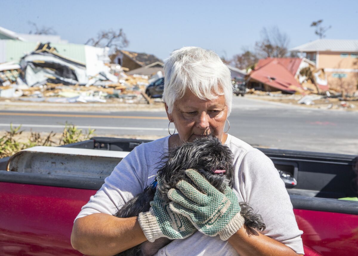 Rebecca Adkisson kisses her dog Bella outside her demolished home in Mexico Beach.