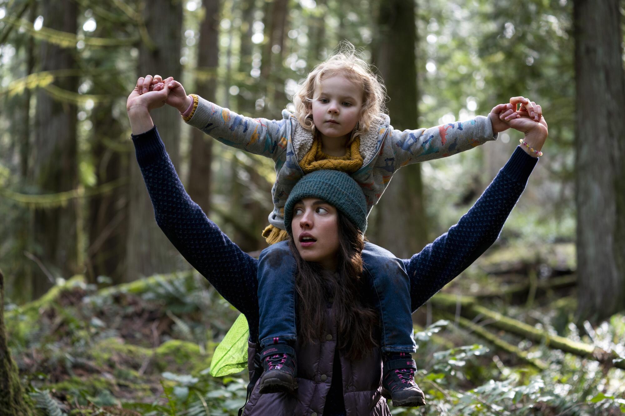 Margaret Qualley carries Rylea Nevaeh Whittet on her shoulders in a walk through the woods in a scene from  "Maid."