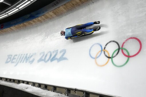 Ukraine's Anton Dukach zips past the Olympic rings during a men's bobsled training race in 2022.