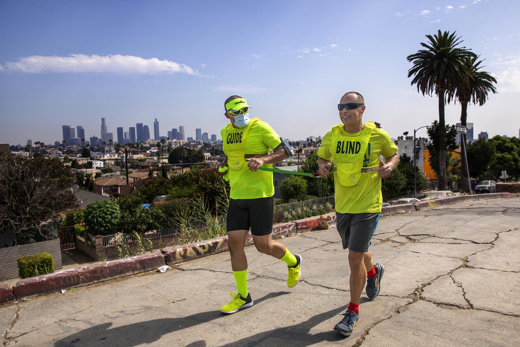 Tony Duenas, right, a marathon runner who is blind, and his guide, Ray Alcanter, jog together on Hoover Street in L.A.