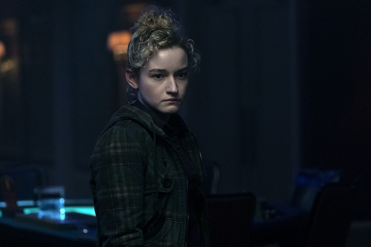 A young woman in a dark room, her face the only part of her in the light.