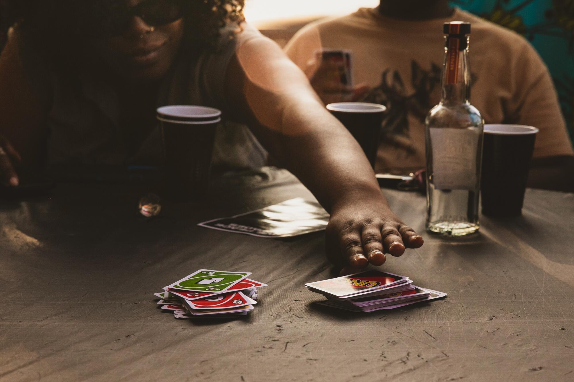 A hand reaches toward a pile of cards on a table.