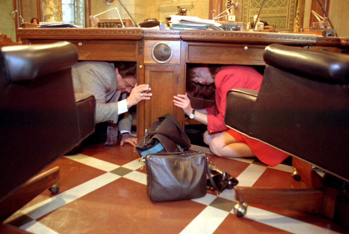Members of the Los Angeles City Council take shelter under their desks during a brief earthquake preparedness drill.