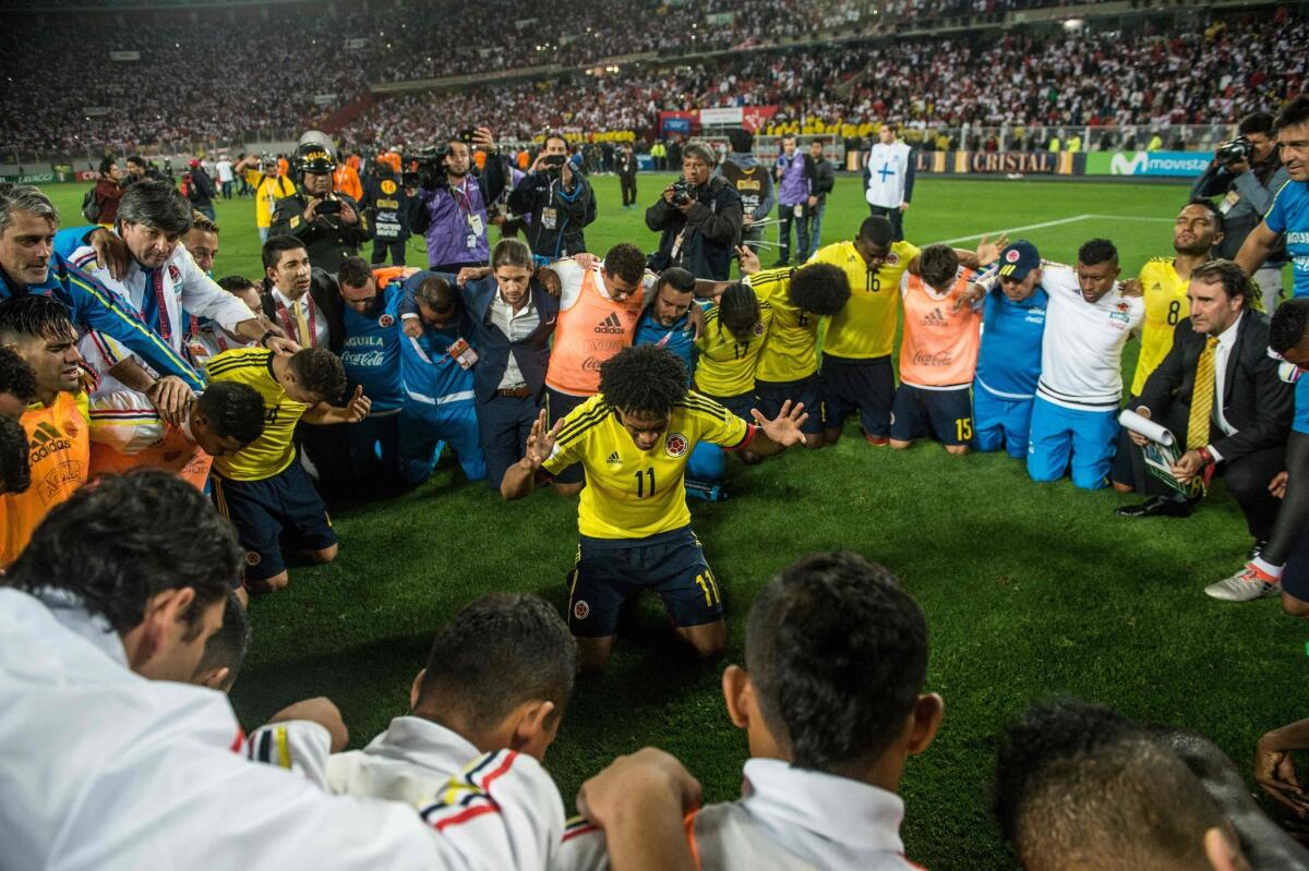 Colombia's footballer Juan Cuadrado (C) leads a prayer after his team qualified for the 2018 World Cup in a tied match (1-1) with Peru in Lima, on October 10, 2017.