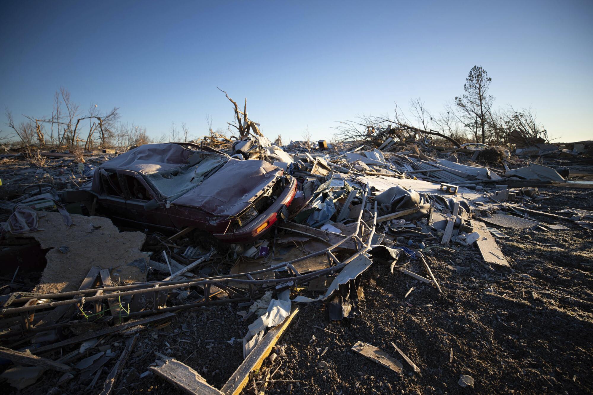 A car sits on the rubble of a destroyed house after a tornado.
