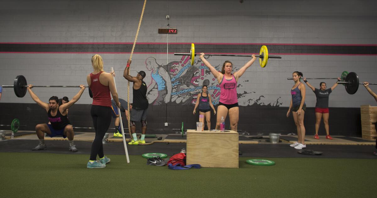 Allison Truscheit, left, observes her clients while they practice barbell lifts.