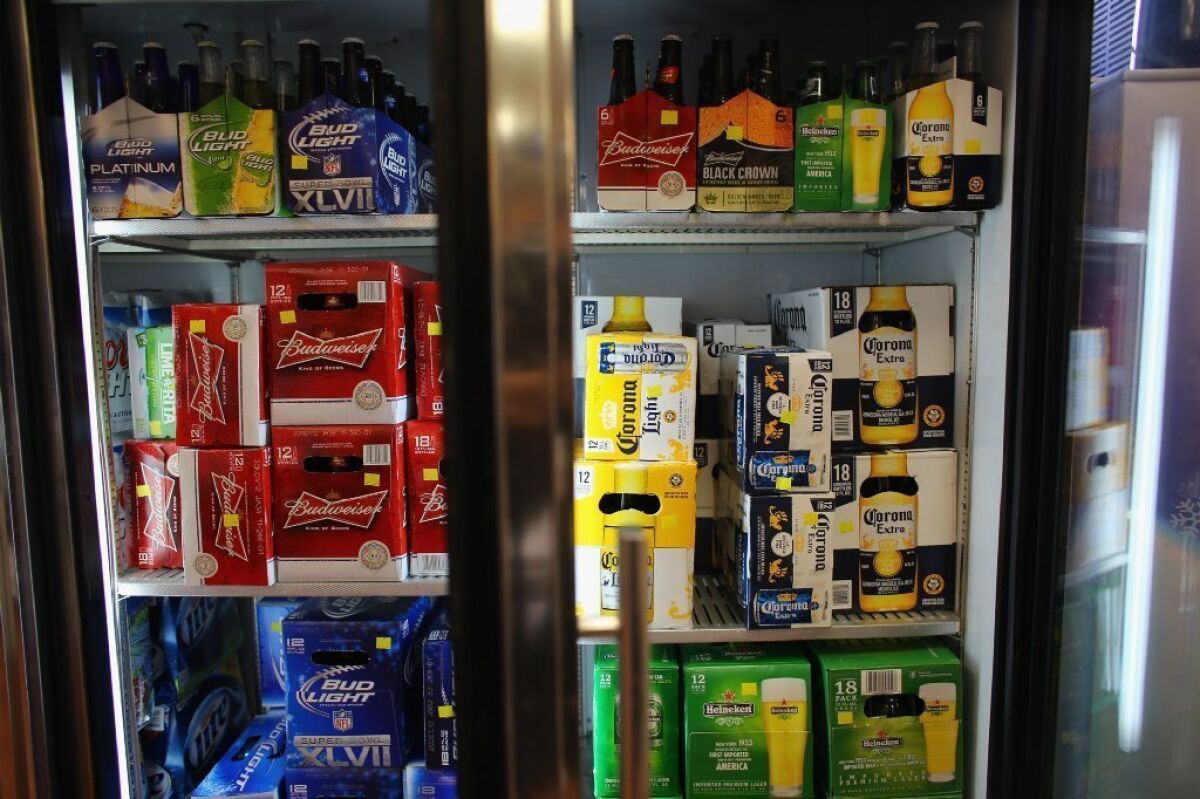 A cooler holds Anheuser-Busch's Budweiser and Grupo Modelo's Corona Light beers at the Chandi Wine and spirits store Thursday in Miami. The Justice Department filed suit to stop Anheuser-Busch InBev's $20.1-billion takeover of Grupo Modelo.