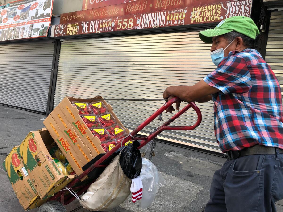 En una carretilla, Mateo Pérez Solís empujaba unas cajas con fresas, bananos y aguacate en unas solitarias calles de L.A.
