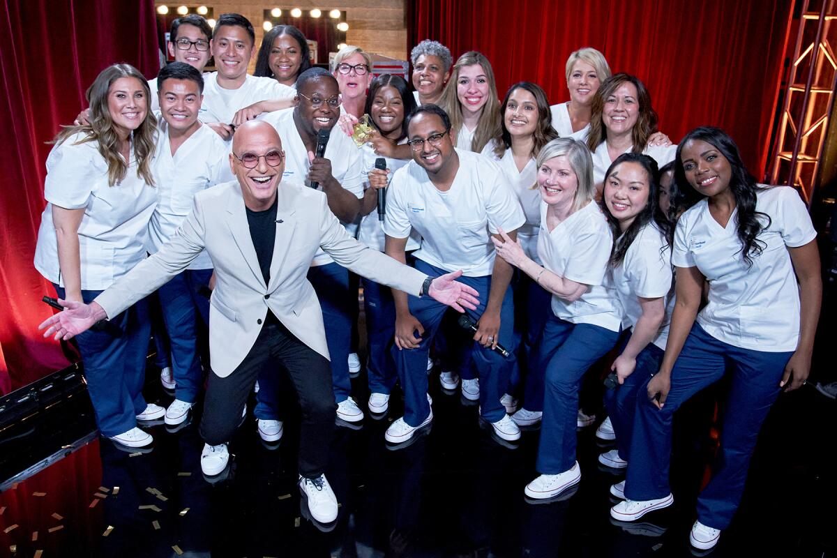 Howie Mandel with singers attired in white shirts and blue jeans