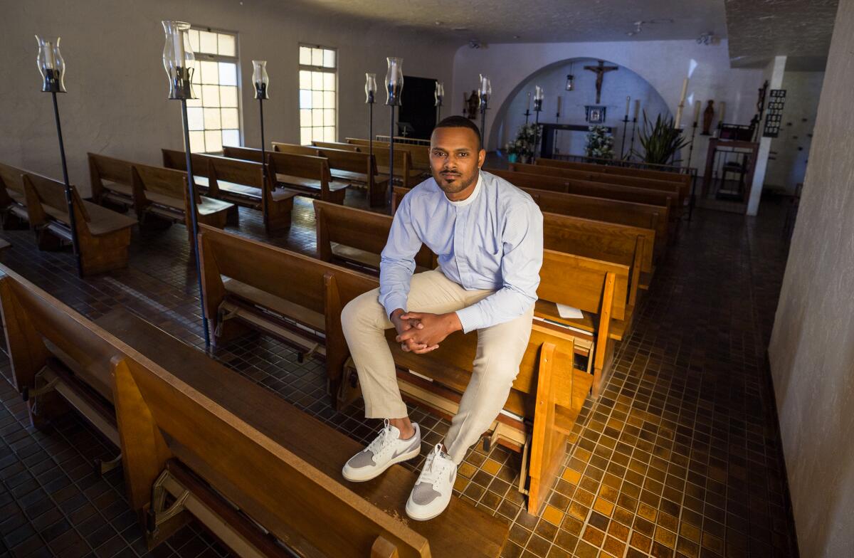 A man sits on a pew in a church.