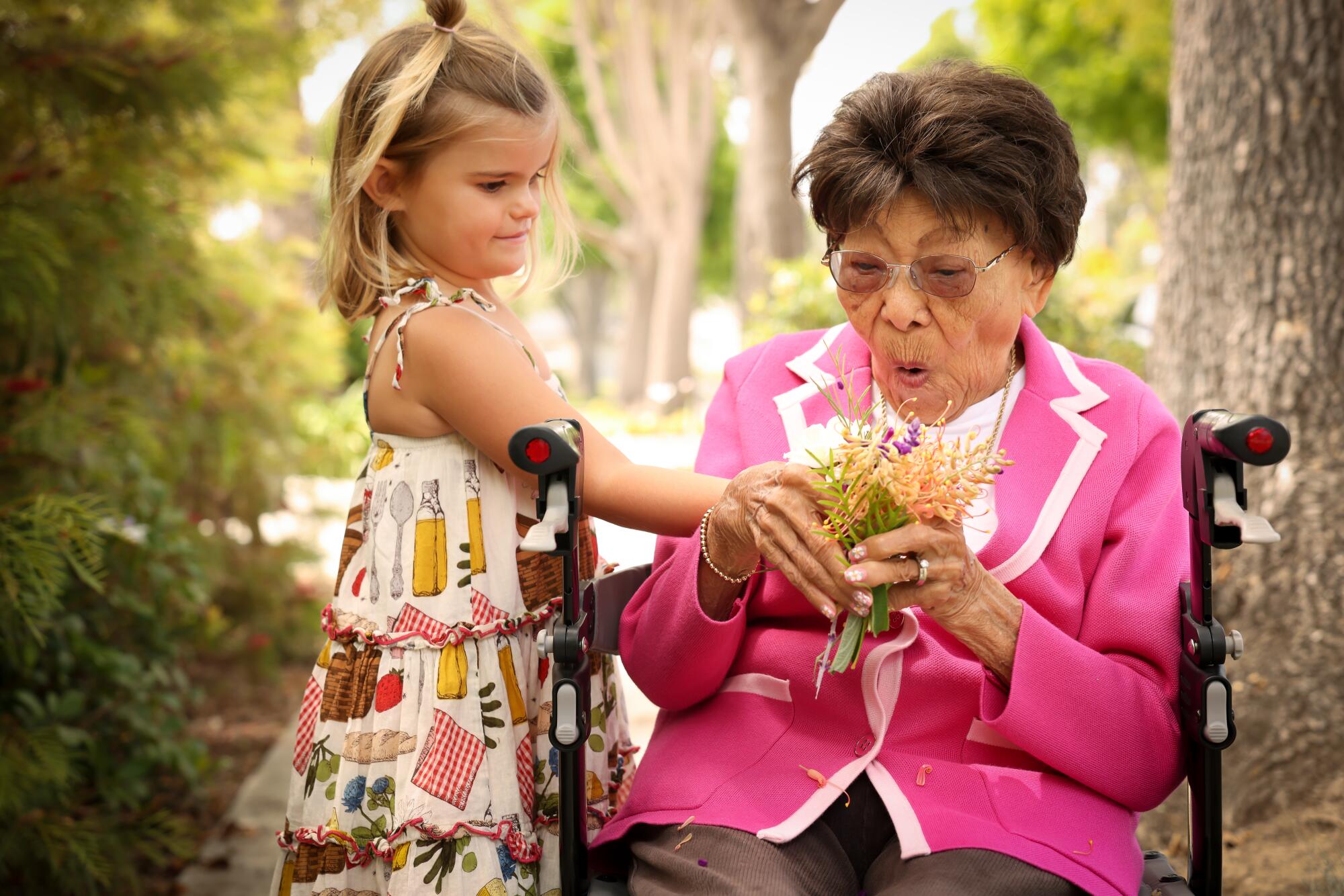 Flora Grewe, 4 1/2, hands her friend Mary Ota, 105, a handful of flowers in Carpinteria.