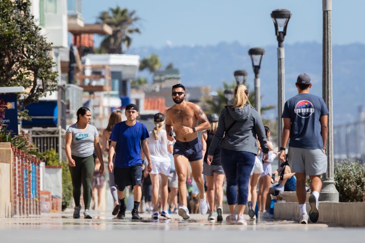 A runner navigates the Strand in Manhattan Beach on Friday. Despite urgings from medical experts and public officials, some walkers and runners disdain face coverings.