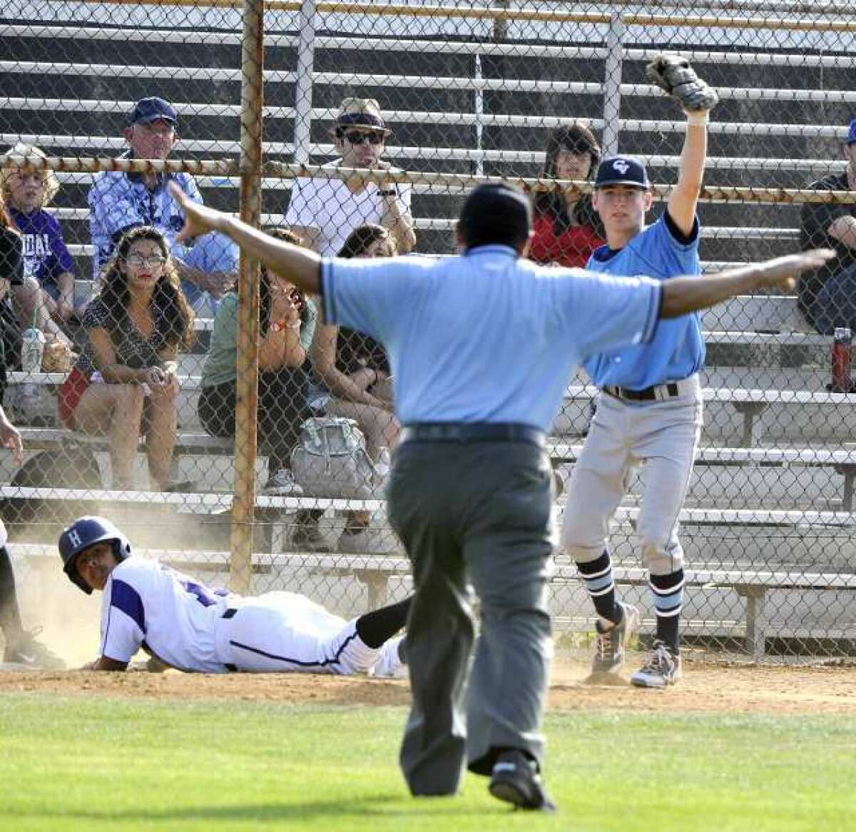 Crescenta Valley third baseman Joe Torres, right, holds up the ball to show the umpire he had it, but the umpire called Hoover runner Luis Zamora safe at third.