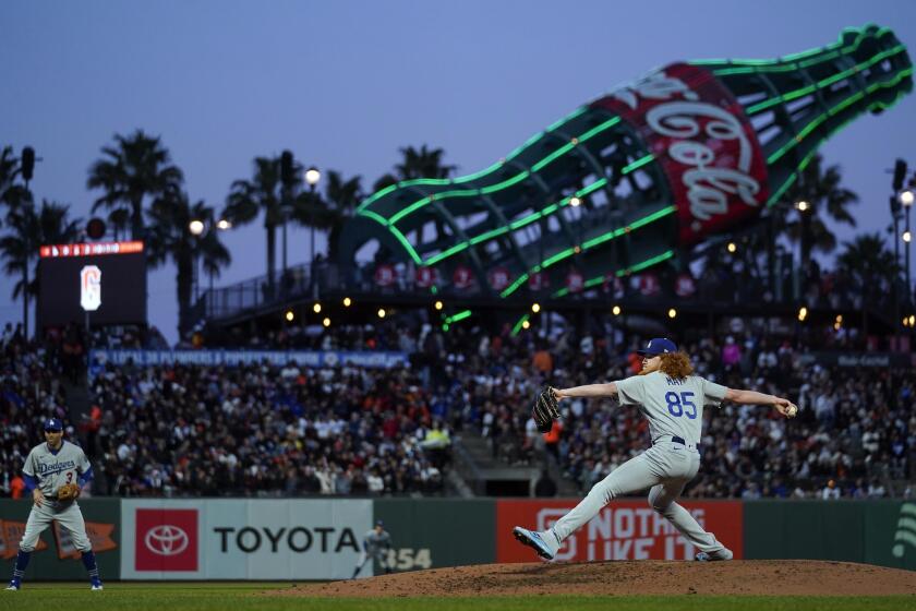 Dodgers pitcher Dustin May throws against the San Francisco Giants, with Oracle Park's giant Coke bottle in the background
