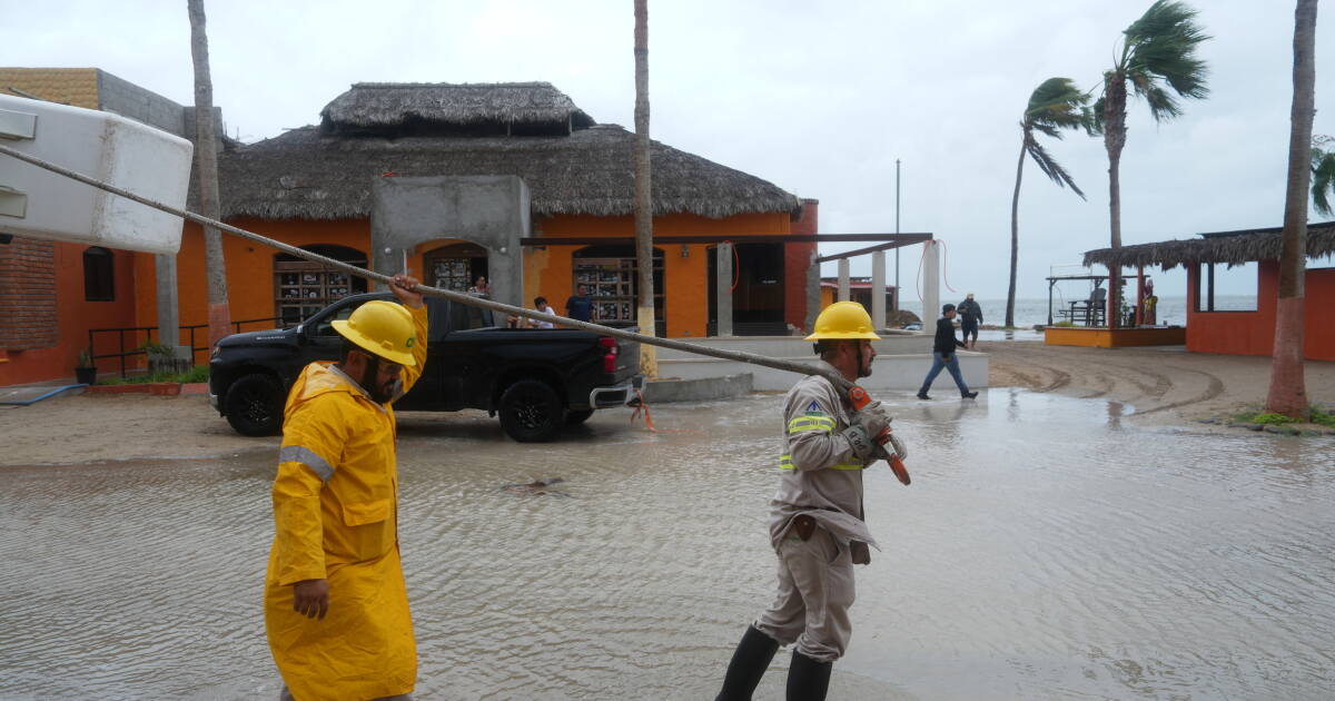 Ein Mann trägt Gegenstände durch die Flut nach dem Vorbeiziehen von Hurrikan Polo in Puerto San Carlos, Baja California Sur. (AP)