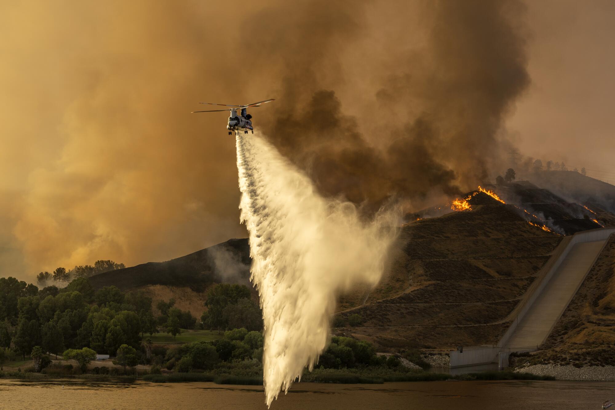 A water-dropping helicopter hovers at the Castaic Lake State Recreation Area while battling the Route fire.