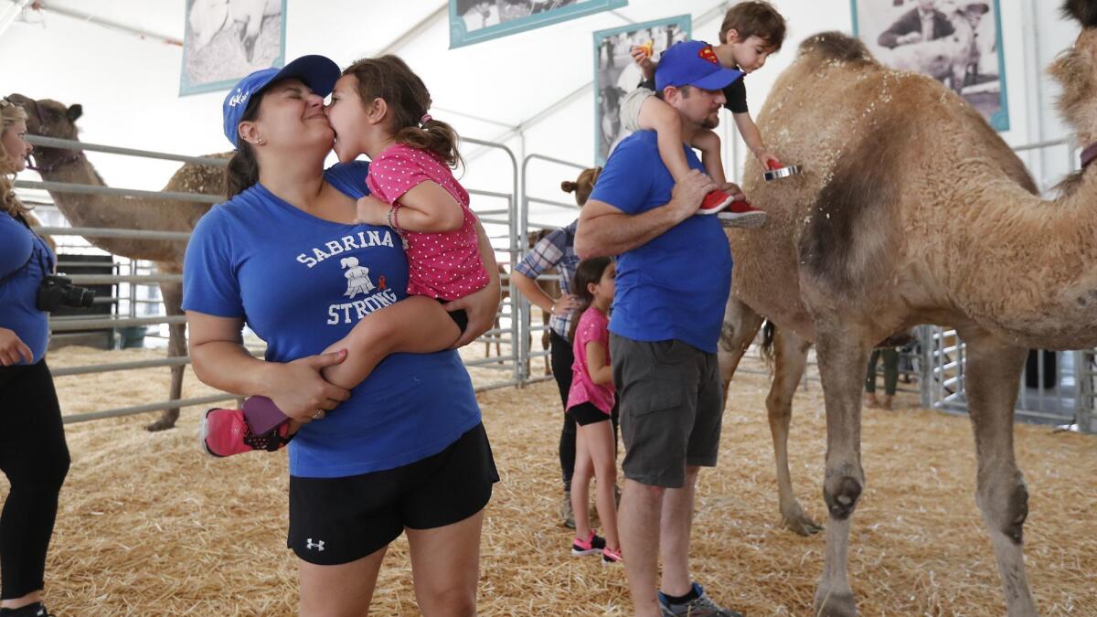 Sabrina Simoes playfully bites her mother, Nora, on the chin as they visit animals at Centennial Farm at the OC Fair & Event Center on Friday.