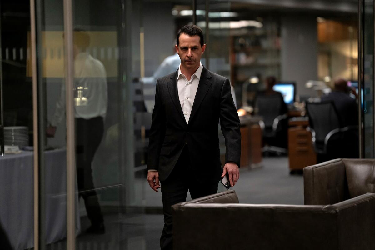 A man in a suit walks away from a busy office in "Succession."