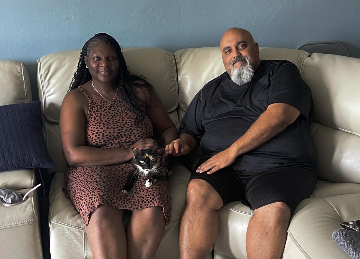 Sherrie, left, and Alfonso Meletiche sit on the couch, while family cat, Baby, takes a rest.