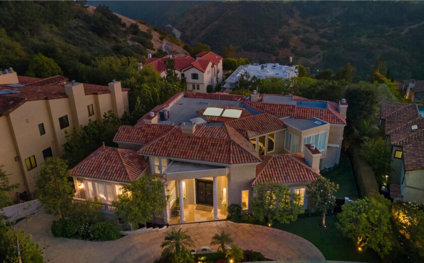 The three-story home includes a movie theater, gym, music studio, brick wine cellar, and waterfall-fed pool.