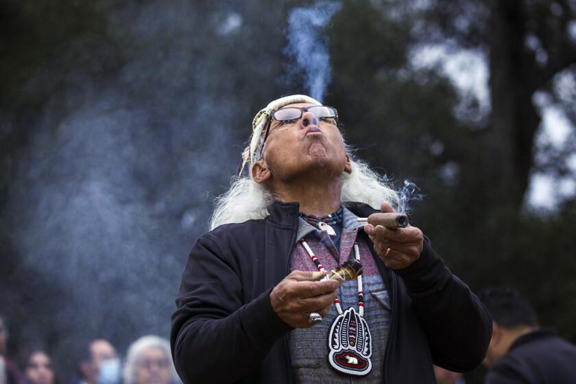 Chatsworth, CA - December 21: Alan Salazar, a Chumash and Tataviam elder, blows sacred tobacco smoke at a Native American prayers held in honor of winter solstice, the shortest day of the year, at Chatsworth Nature Reserve in Chatsworth, CA. (Irfan Khan / Los Angeles Times)