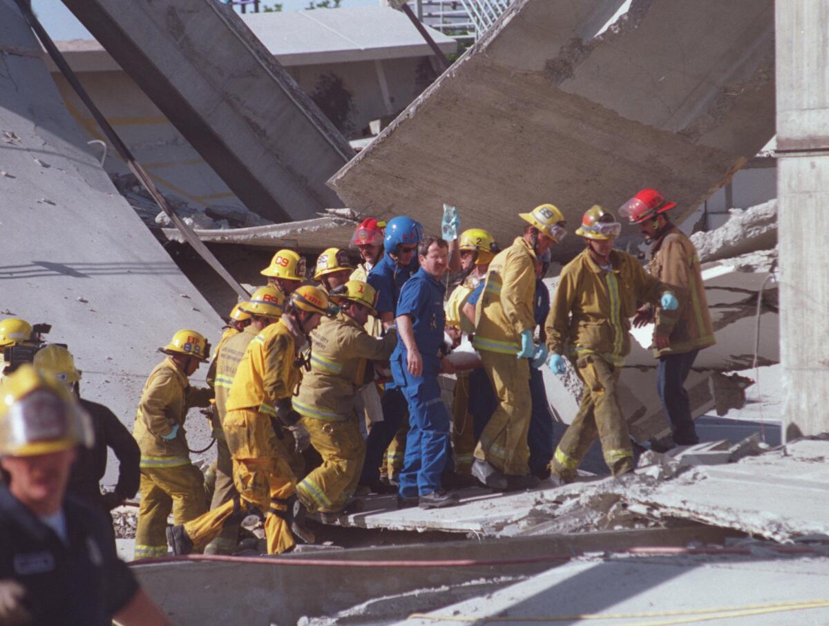 Rescue team members carry Salvador Pena (cq) away from collapsed garage at Northridge Fashion Center