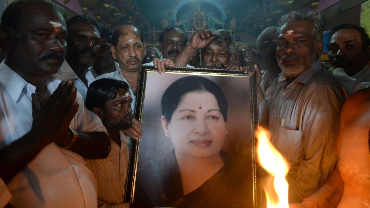 Supporters hold a photograph of Jayaram Jayalalithaa as they offer prayers for her well-being at a temple in Mumbai, India.
