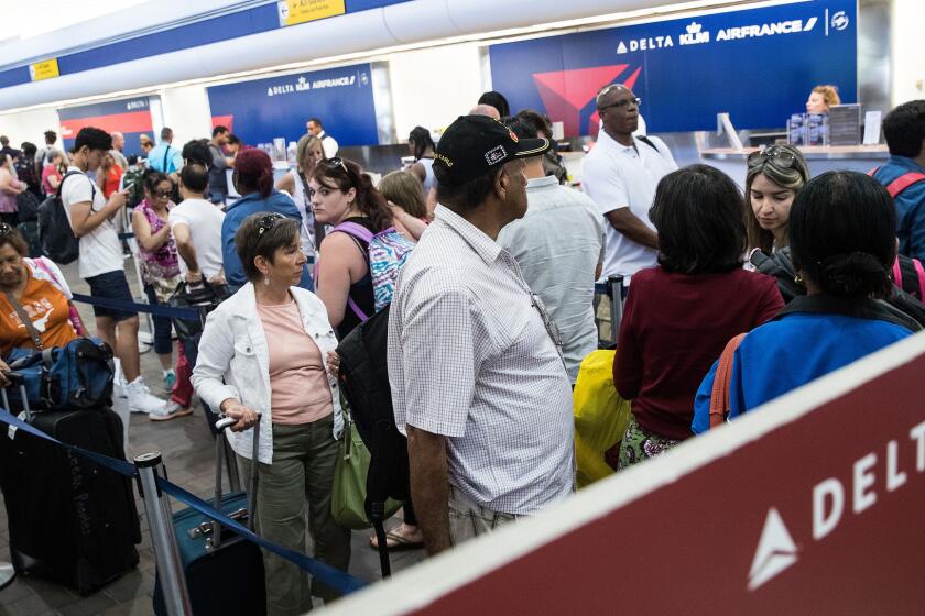 Travelers wait in line at the Delta check-in counter at LaGuardia Airport on Monday.