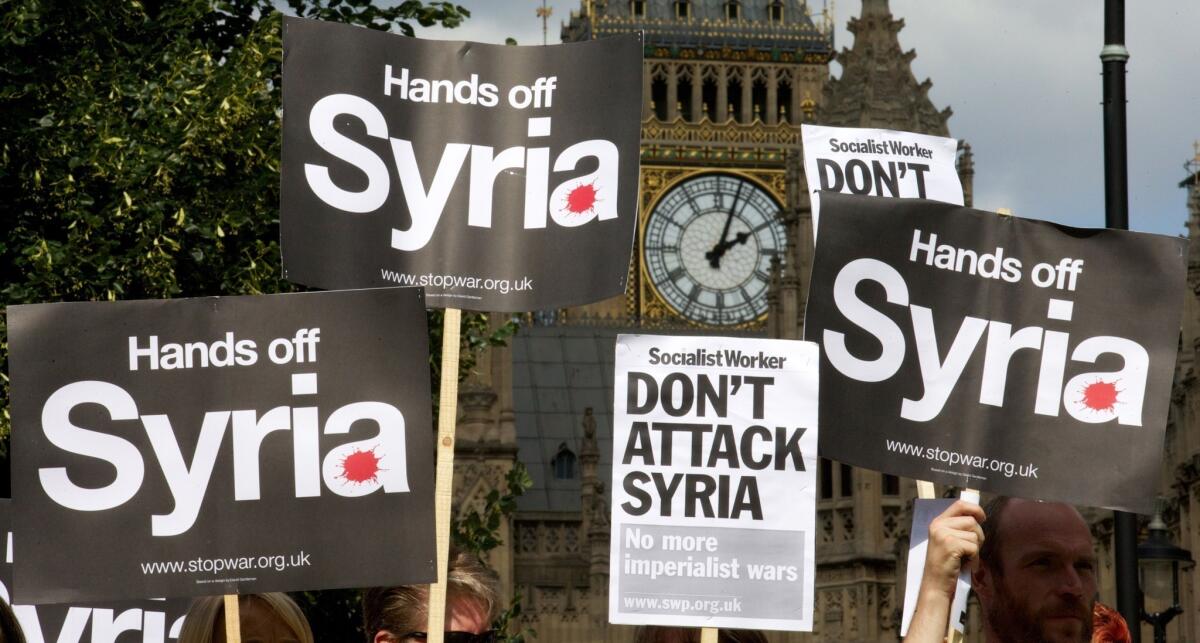 Demonstrators hold up placards protesting against any British military involvement in Syria outside the Houses of Parliament in London.