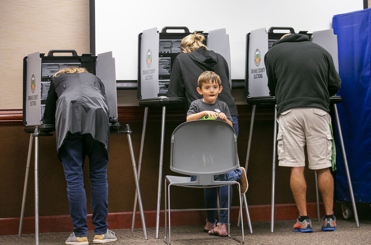 Zeign Schmidt patiently waits as his mother, Pepper, casts her ballot at the Huntington Beach City Hall on Election Day.