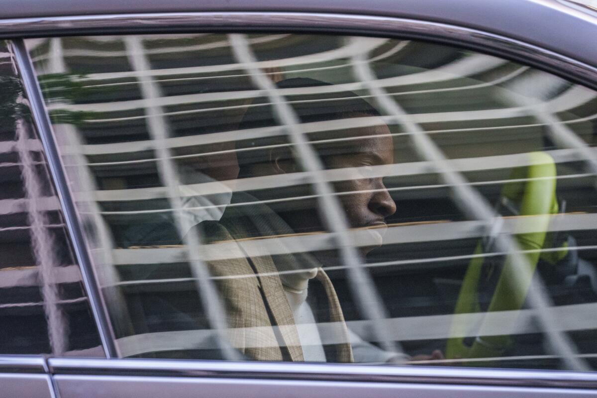 A man seen through the front passenger window of a vehicle.