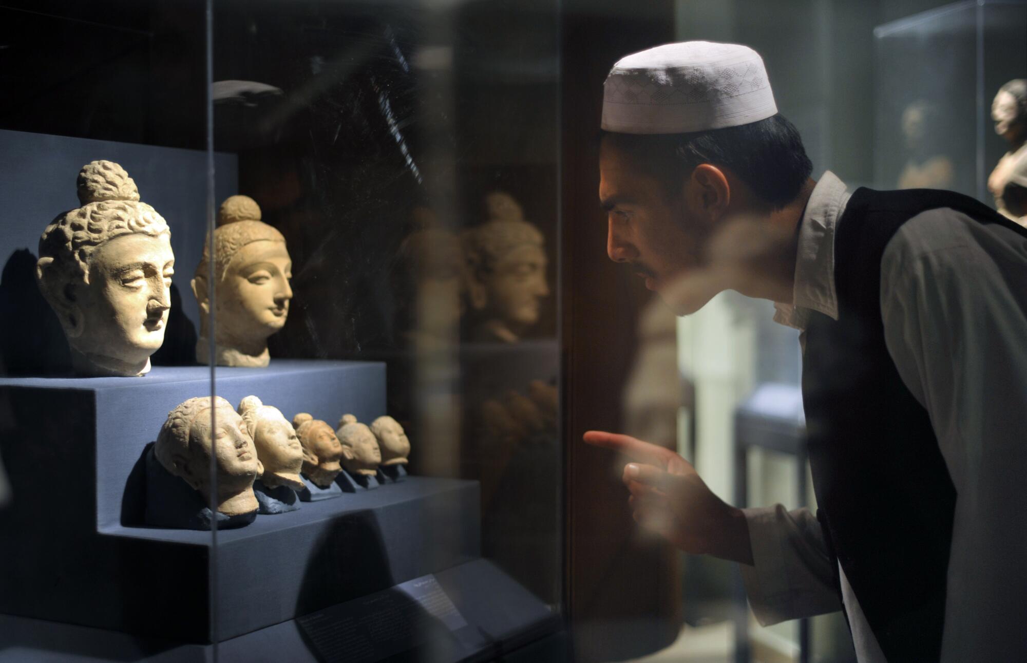An Afghan student scrutinizes a display of Buddha in a glass vitrine