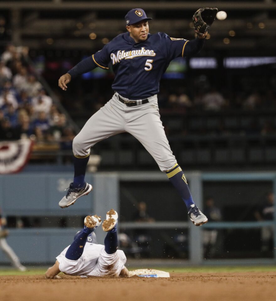 Dodgers baserunner Chris Taylor dives ahead of a second inning pickoff attempt from Brewers catcher Manny Pina to shortstop Orlando Arcia.
