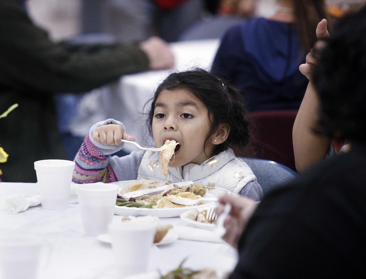 Anabelle Reyes, 4, of Burbank, takes a big bite of a big slice of turkey at The Burbank Salvation Army for the annual Thanksgiving dinner on Wednesday, November 21, 2018.