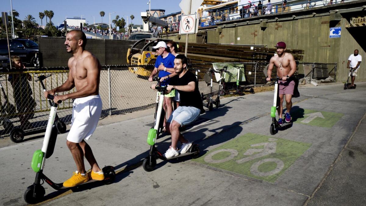 People ride Lime and Bird scooters in Santa Monica in July.