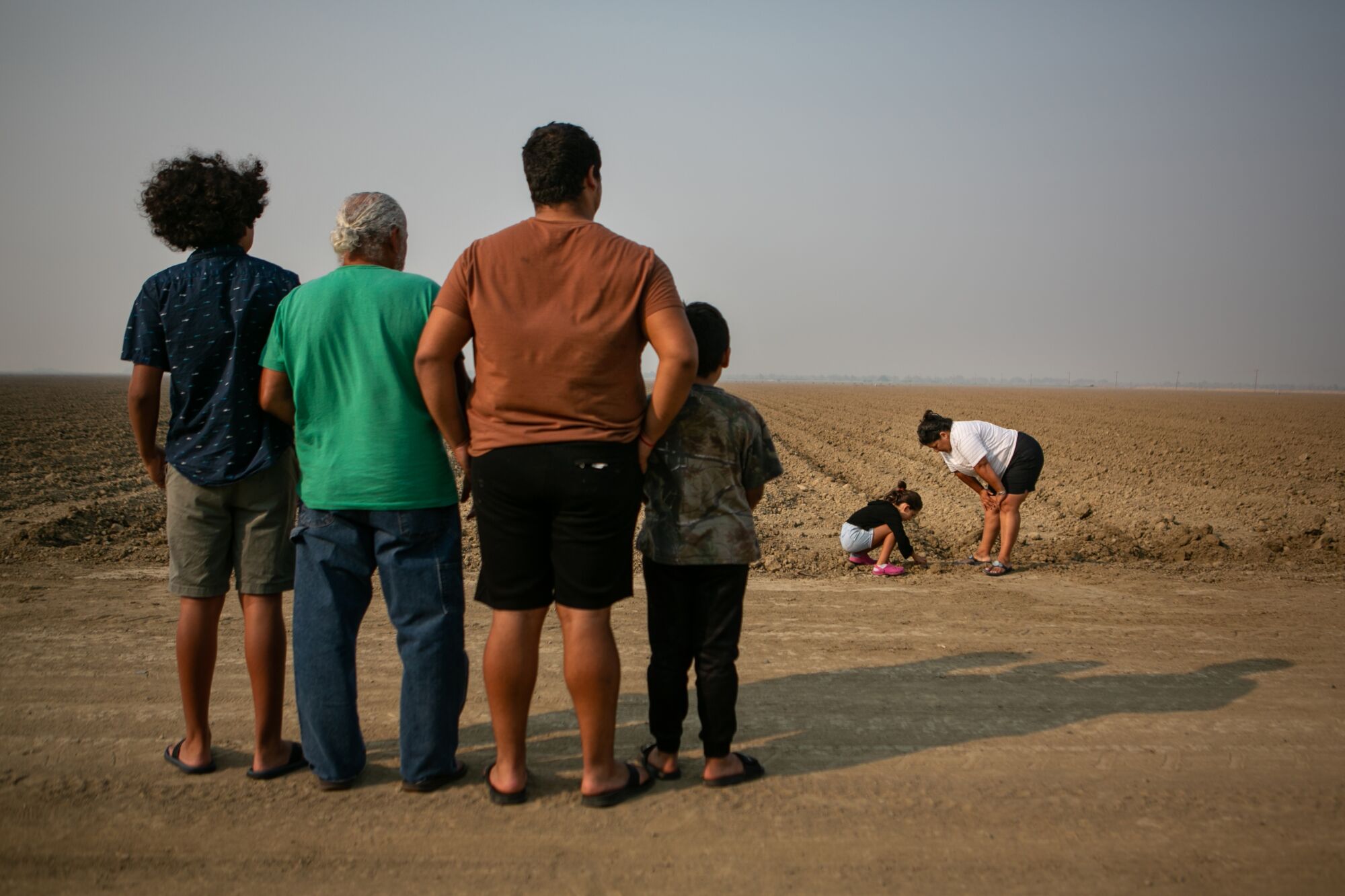 The family watches as a girl plays in a field
