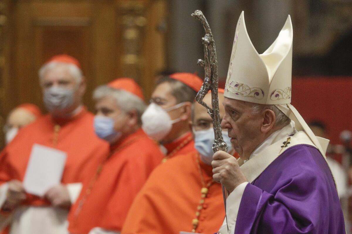 Pope Francis arrives to celebrate Mass at St. Peter's Basilica in Vatican City while cardinals stand near him.