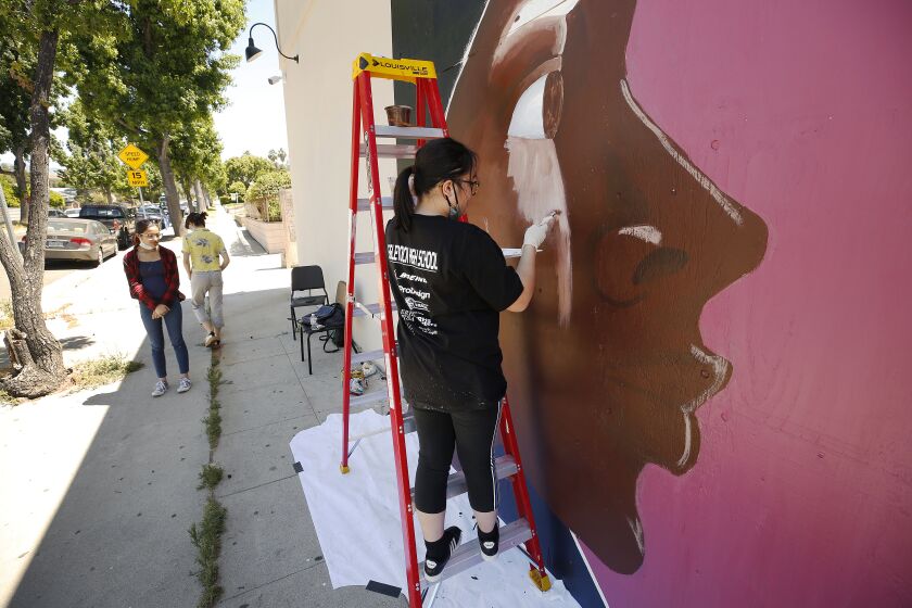LOS ANGELES, CA - JUNE 09: Eagle Rock High School student Lucia Sano, 14, paints a mural of a Black Woman's profile on a store front in support of the Black Lives Matter movement on Tuesday June 9, 2020 in the Highland Park neighborhood. Assisted by her classmates Sienna Williams, 15, and Sofia Tong, 15, the students are painting murals of support on the storefronts of some restaurants that are under construction. Highland Park on Tuesday, June 9, 2020 in Los Angeles, CA. (Al Seib / Los Angeles Times)
