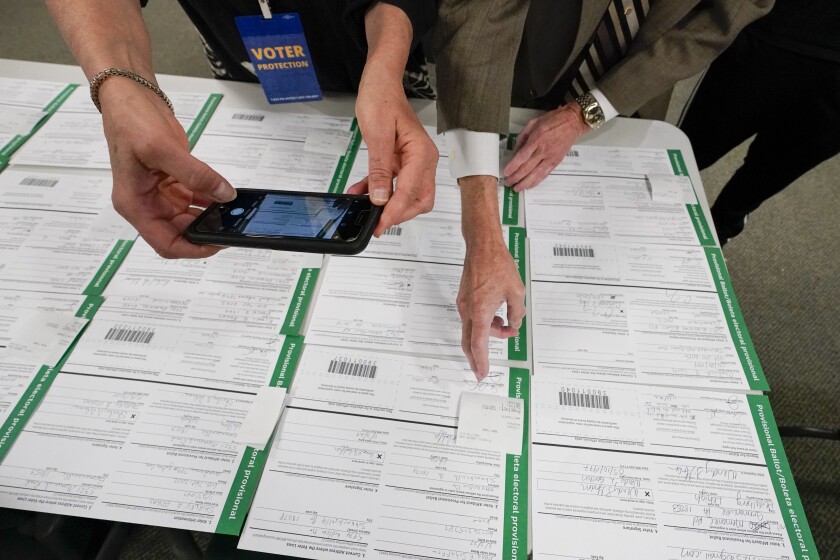 An observer photographs provisional ballots.