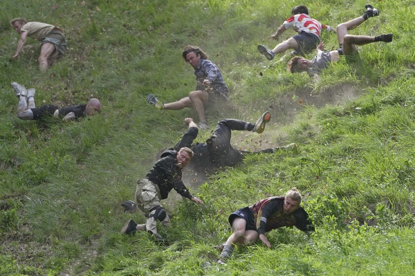 Participants compete in the men's downhill race during the Cheese Rolling contest at Cooper's Hill in Brockworth, Gloucestershire, Monday May 29, 2023. The Cooper's Hill Cheese-Rolling and Wake is an annual event where participants race down the 200-yard (180 m) long hill chasing a wheel of double gloucester cheese. (AP Photo/Kin Cheung)