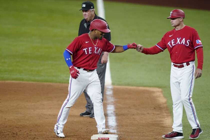 Texas Rangers' Andy Ibanez and first base coach Corey Ragsdale, right, celebrate Ibanez's RBI single during the sixth inning of the team's baseball game against the Oakland Athletics in Arlington, Texas, Friday, July 9, 2021. Umpire Joe West stands at rear. (AP Photo/Tony Gutierrez)