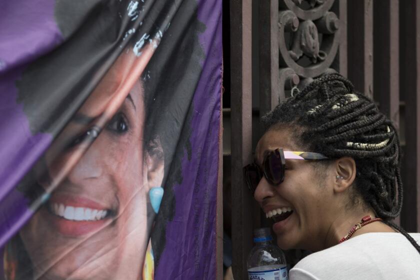 A woman cries next to a banner with an image of councilwoman Marielle Franco at the entrance of City Hall where thousands people gather to pay their respects to the slain 38-year-old and her driver who were both gunned down the night before by two unidentified attackers, in Rio de Janeiro, Brazil, Thursday, March 15, 2018. (AP Photo/Leo Correa)