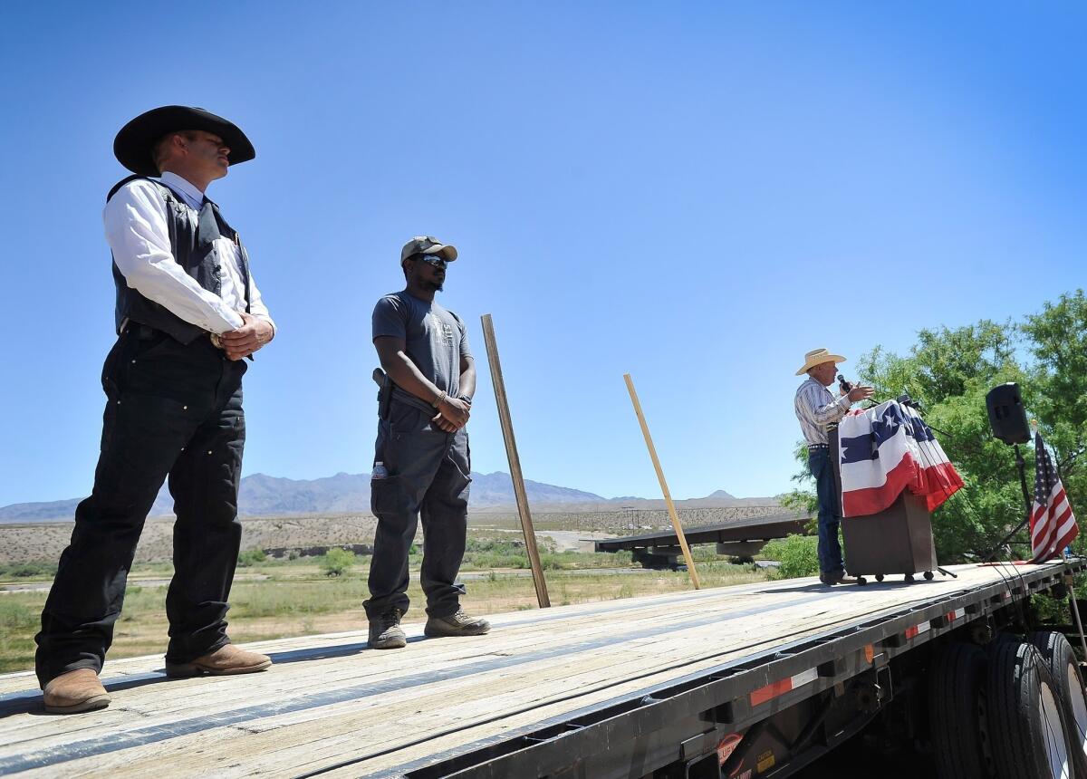 Rancher Cliven Bundy, with two supporters, speaks at a news conference Thursday near his ranch in Bunkerville, Nev.