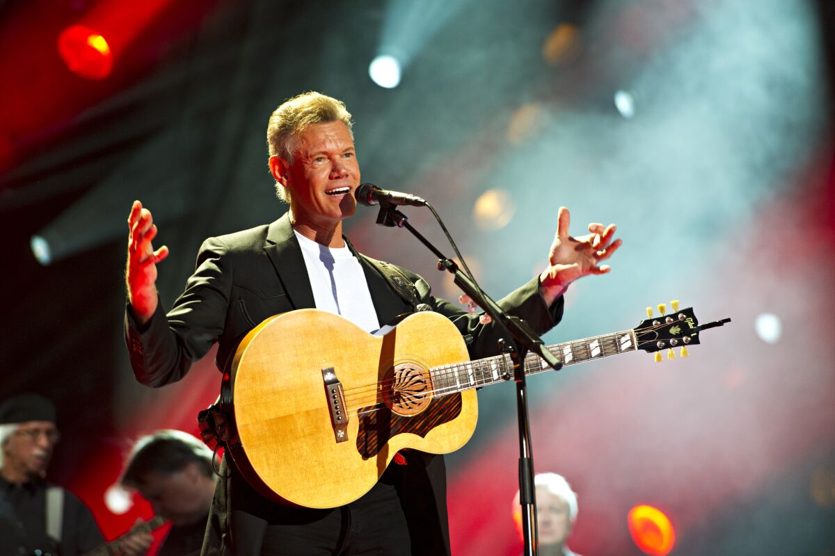 A man standing in front of a microphone wearing a suit and guitar
