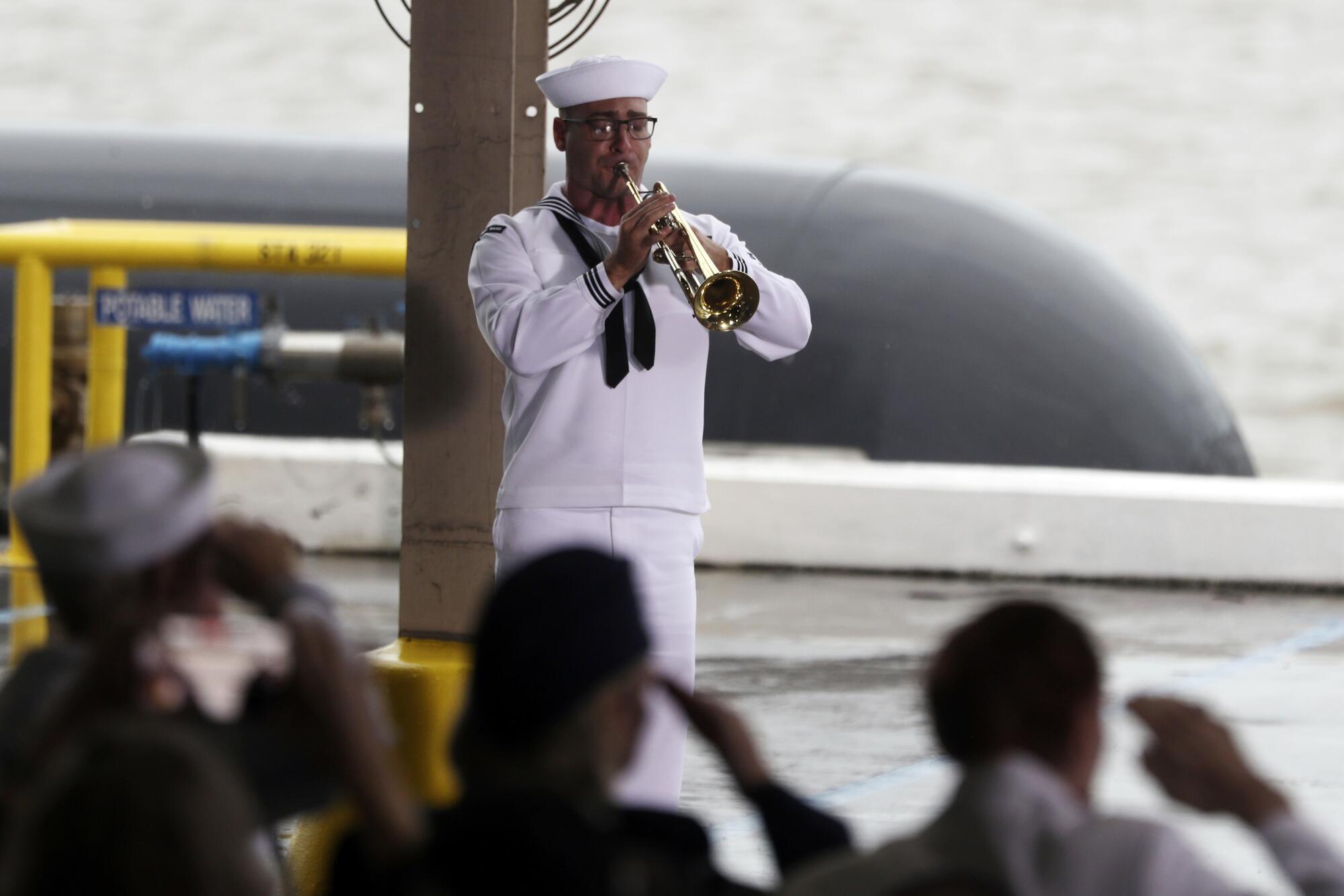 A Navy sailor plays taps at the ceremony