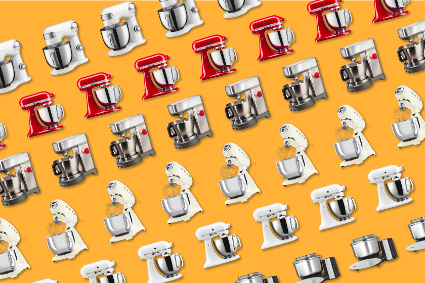 Row of various stand mixers arranged in front of an orange background