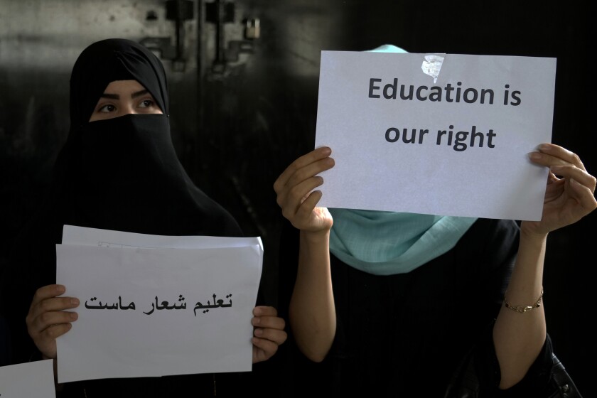 Afghan girls holding protest signs demanding the right to an education