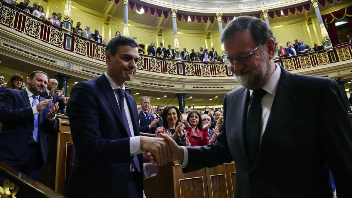 Prime Minister Pedro Sanchez, left, shakes hands with former Prime Minister Mariano Rajoy after Sanchez won the no-confidence motion Friday.